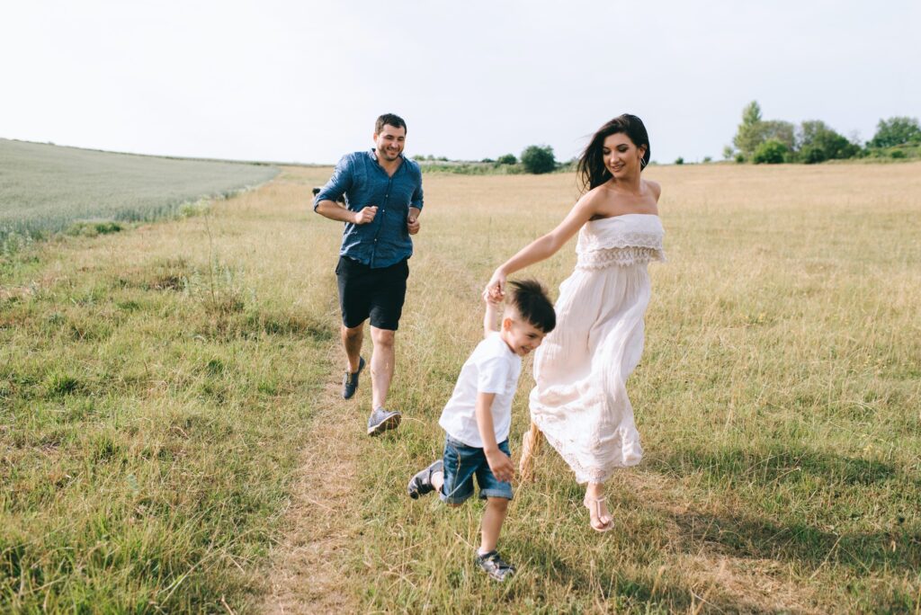 happy parents and son running on field