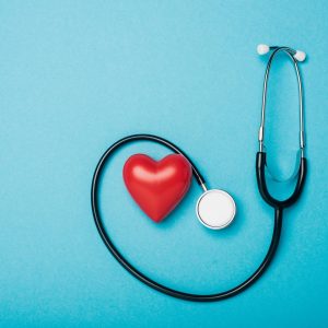 Top view of decorative heart and stethoscope on blue background, world health day concept